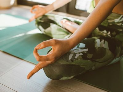 Close-up of a person's hands in a meditative pose on a yoga mat.
